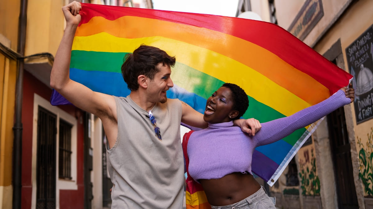 Pareja celebrando con bandera arcoíris LGTBIQ+ en calle de Ibiza, colectivo Sa Clau de s'Armari